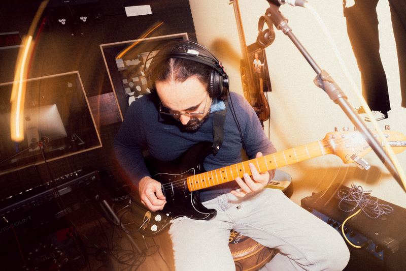 Guitarist in headphones recording in the studio among warm light trails