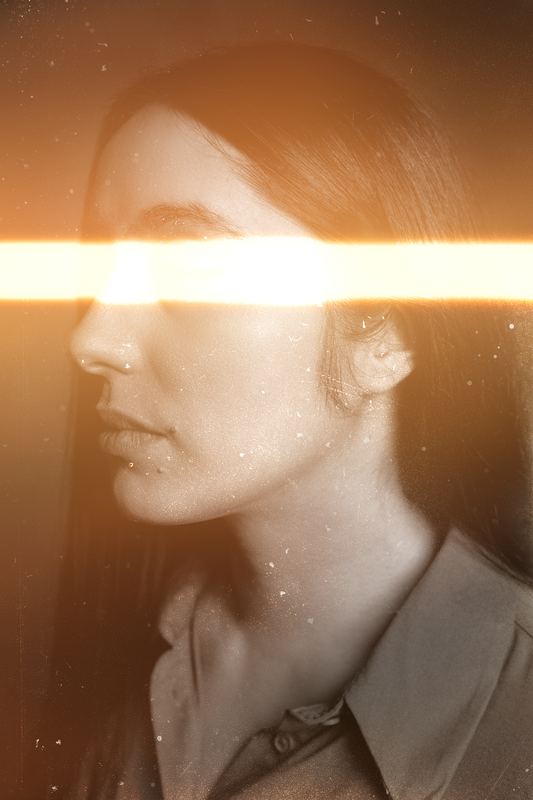 Profilo di donna attraversato da una lama di luce arancione, toni seppia